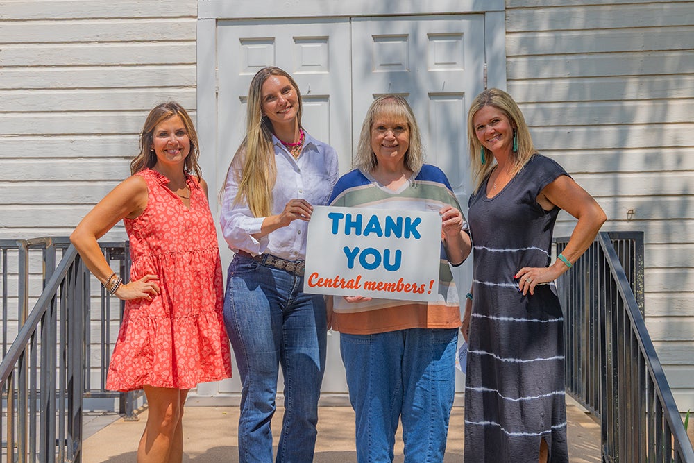 Central Rural Electric Cooperative trustee Melanie McGuire and Central Community Foundation board member Lyndee Strader present Cherokee Strip executive director, Maddy Flores, and Rose Hill schoolhouse coordinator, Denise Lovely, with a foundation grant in front of the Rose Hill schoolhouse.
